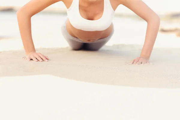 Frau macht Liegestütze am Strand — Stockfoto