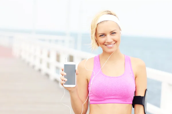 Mujer joven mostrando el teléfono sobre el muelle —  Fotos de Stock