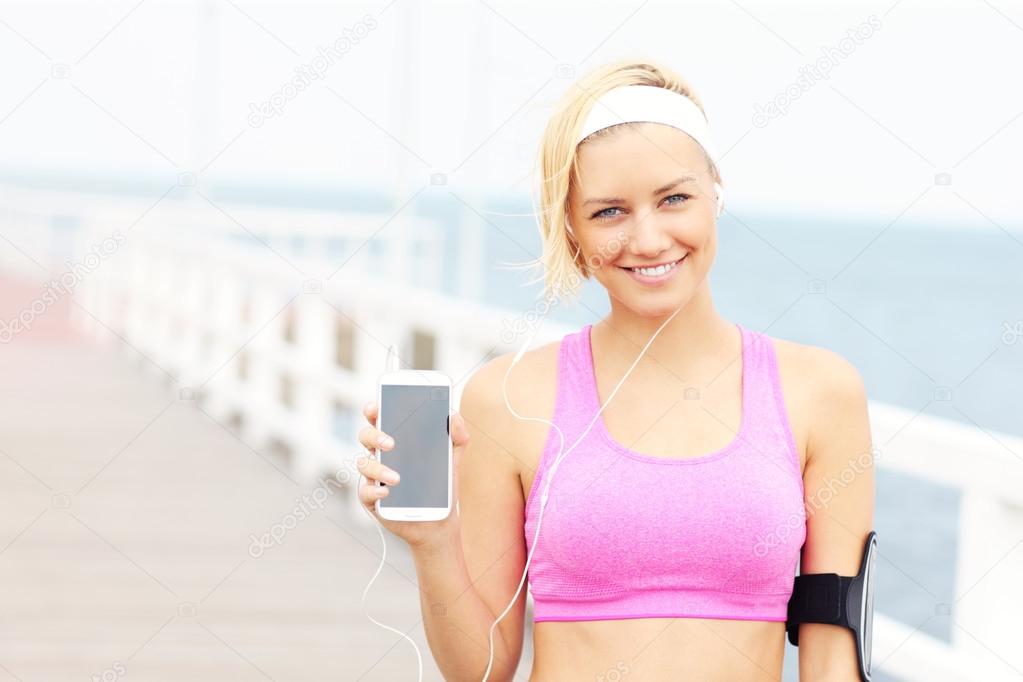 Young woman showing phone over pier