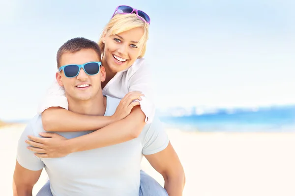 Freudiges Paar, das sich am Strand umarmt — Stockfoto