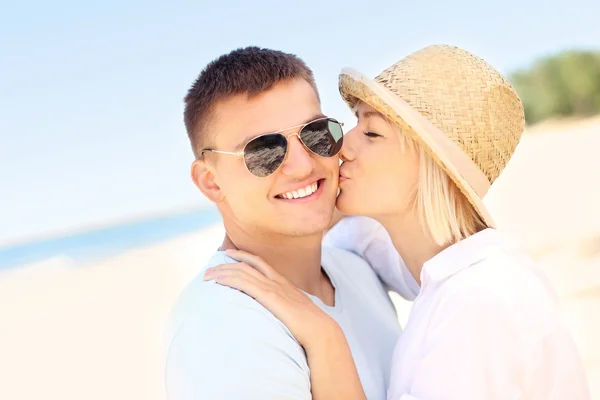 Woman kissing a man at the beach — Stock Photo, Image