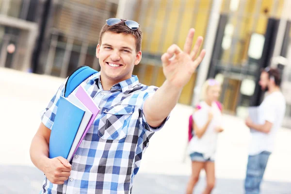 Yakışıklı öğrenci ok işareti kampüs içinde gösterilen — Stok fotoğraf