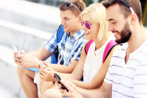 Groep van vrienden met behulp van smartphones in de campus — Stockfoto