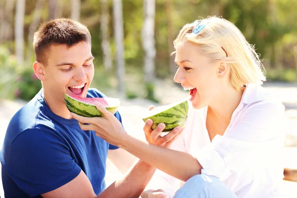 Glückliches Paar isst Wassermelone am Strand — Stockfoto