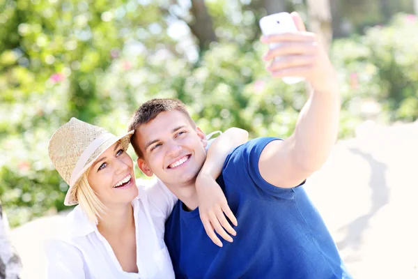 Jeune couple prenant une photo d'eux-mêmes à la plage — Photo