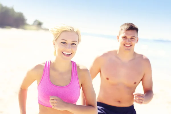 Jeune couple joyeux jogging le long de la plage — Photo