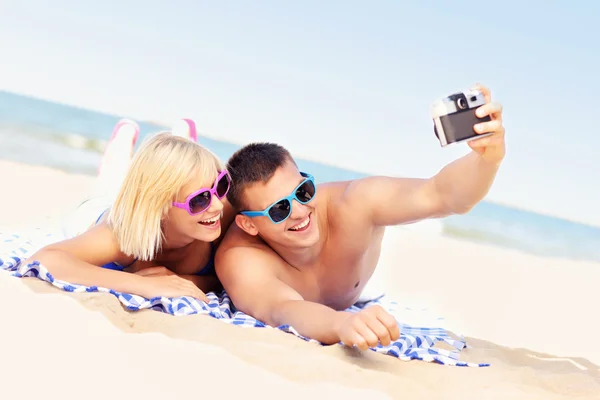 Happy couple taking pictures at the beach — Stock Photo, Image