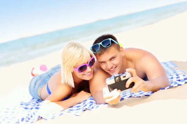 Young couple taking pictures at the beach — Stock Photo, Image