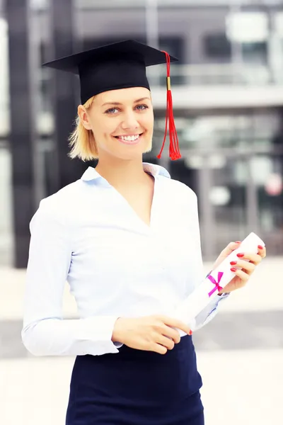 Happy graduate standing outside modern building — Stock Photo, Image