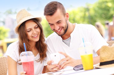 Mutlu çifte bir kafede Smartphone kullanarak