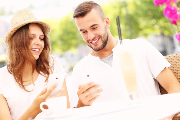 Coppia felice con i loro smartphone in un caffè — Foto Stock