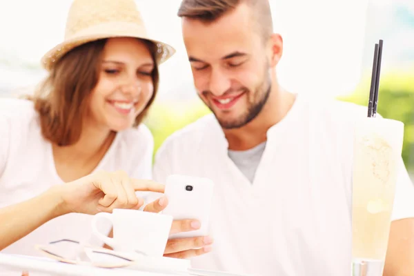 Gelukkige paar met hun smartphones in een café — Stockfoto