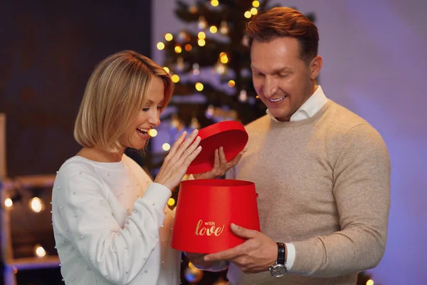 Couple giving christmas gift in front of a tree — Stock Photo, Image