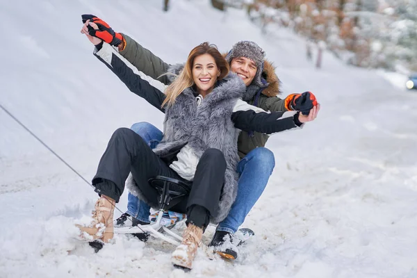 Pareja divirtiéndose con trineo en la nieve en invierno — Foto de Stock