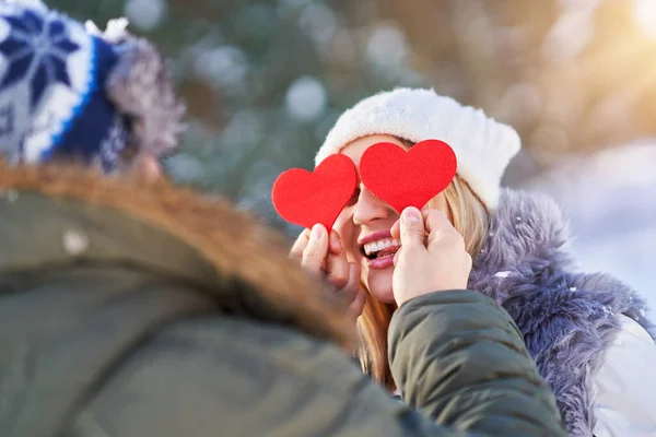 Casal com corações vermelhos no inverno cenário nevado — Fotografia de Stock