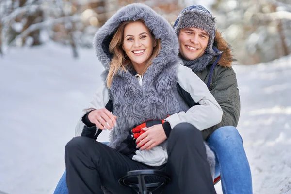 Пара веселится с санями на снегу зимой — стоковое фото