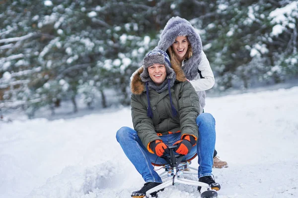 Пара веселится с санями на снегу зимой — стоковое фото
