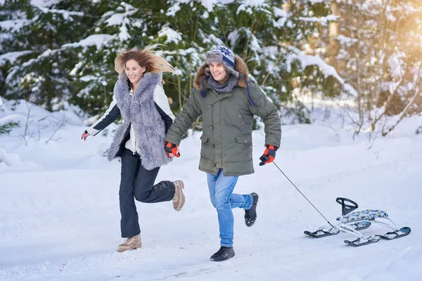 Paar vergnügt sich im Winter mit Schlitten auf Schnee — Stockfoto