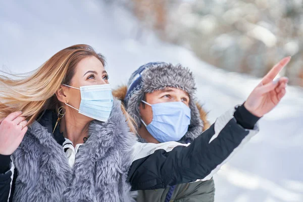 Young couple having fun on snow wearing mask — Stock Photo, Image