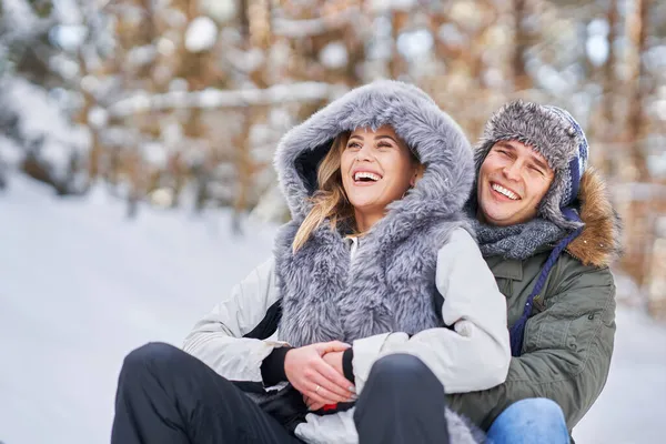 Pareja divirtiéndose con trineo en la nieve en invierno —  Fotos de Stock