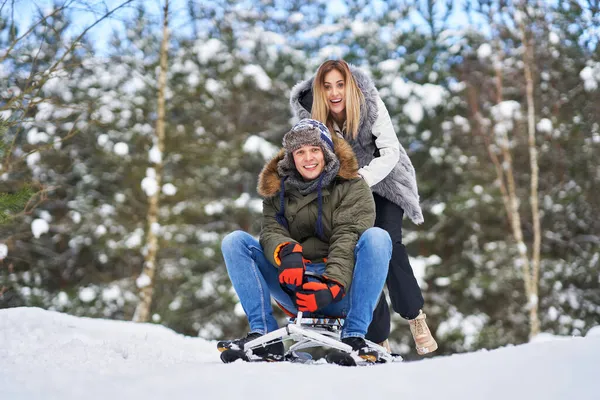 Pareja divirtiéndose con trineo en la nieve en invierno — Foto de Stock