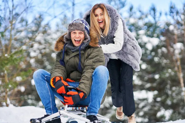 Пара розважається з санчатами на снігу взимку — стокове фото