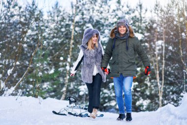 Çift kışın karda kızakla eğleniyor.