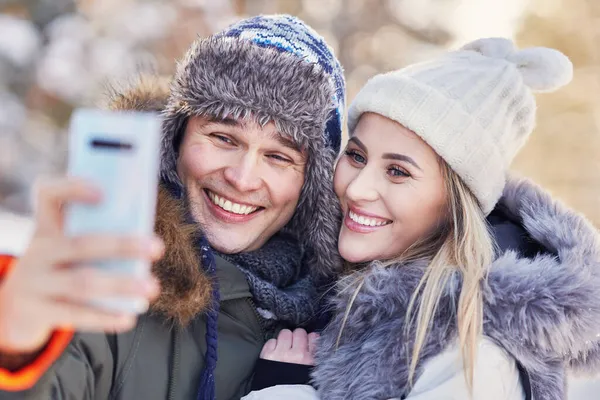 Jeune couple s'amuser sur la neige prendre selfie — Photo