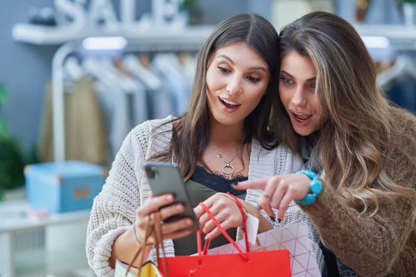 Groep van gelukkige vrienden tijdens het winkelen met de telefoon — Stockfoto