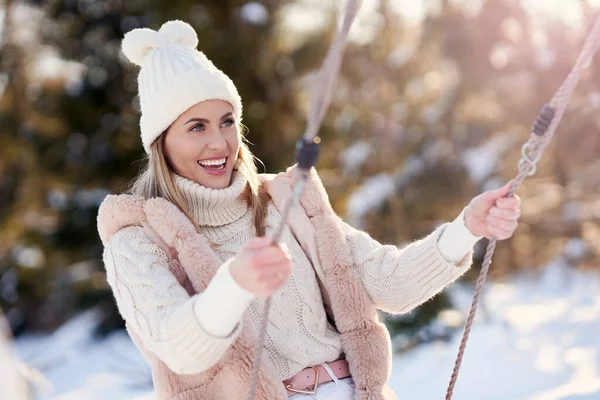 Jovem mulher feliz agradável no cenário de inverno no balanço — Fotografia de Stock