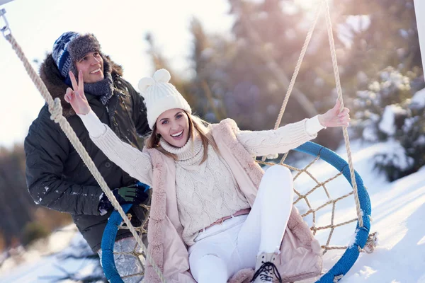 Paar plezier hebben in de winter sneeuw op swing — Stockfoto