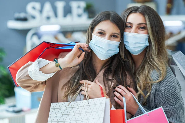 Ragazze a fare shopping in negozio con vestiti che indossano maschere — Foto Stock