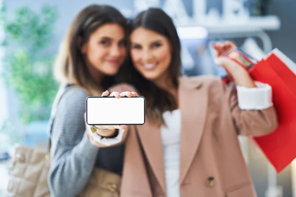 Dos chicas felices en compras sosteniendo el teléfono — Foto de Stock