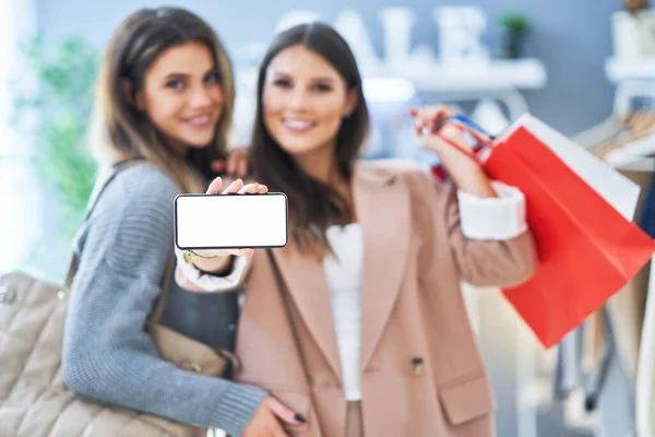 İki mutlu kız ellerinde telefonla alışveriş yapıyor. — Stok fotoğraf