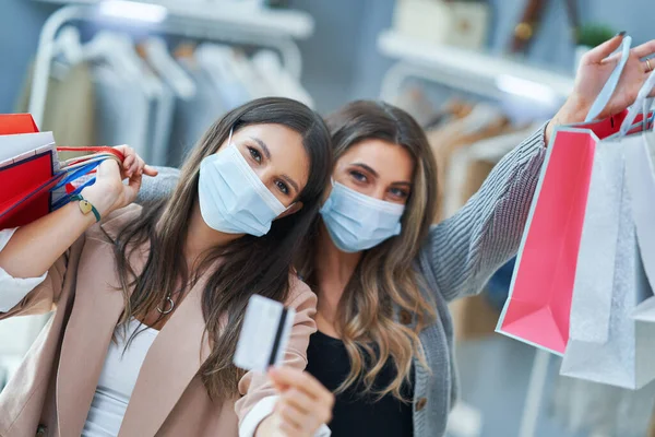 Meninas em compras na loja com roupas usando máscaras — Fotografia de Stock