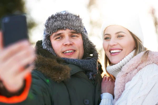 Casal jovem se divertindo na neve tomando selfie — Fotografia de Stock