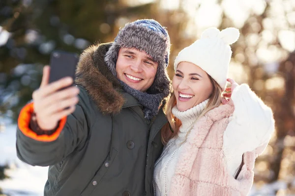 Genç çift karla eğleniyor ve selfie çekiyor. — Stok fotoğraf