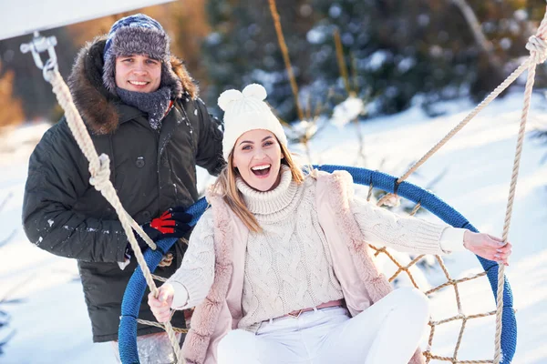 Paar plezier hebben in de winter sneeuw op swing — Stockfoto