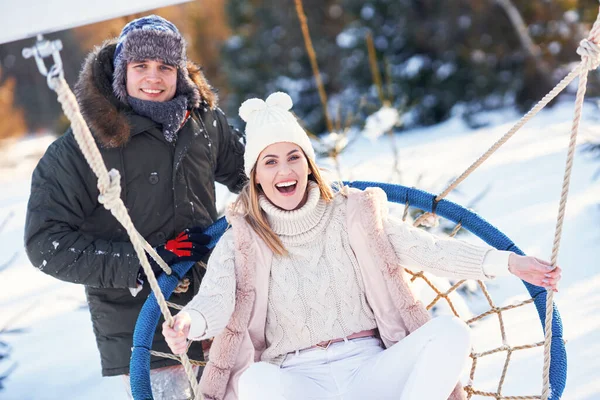 Couple s'amuser en hiver neige sur balançoire — Photo