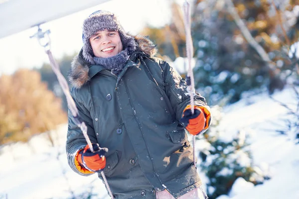 Νεαρός όμορφος άντρας διασκεδάζει στο swing στο χειμερινό τοπίο — Φωτογραφία Αρχείου