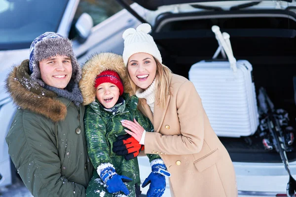 Genç bir aile kış gezisi sırasında arka planda bir araba bagajında — Stok fotoğraf