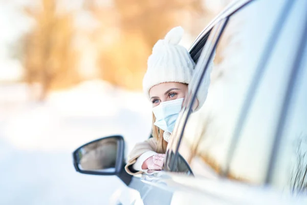 Happy woman driving car in snowy winter wearing mask — Stock Photo, Image