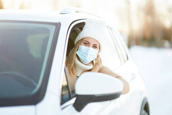 Happy woman driving car in snowy winter wearing mask — Stock Photo, Image