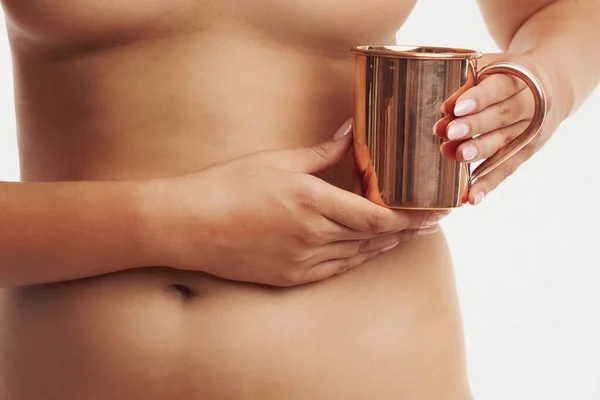 Woman holding copper copper utensils in front of body skin — Stockfoto