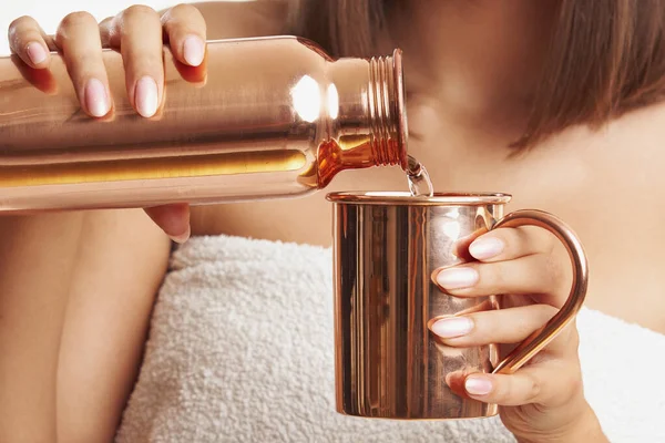 Woman holding copper copper utensils in front of body skin — Stock Photo, Image