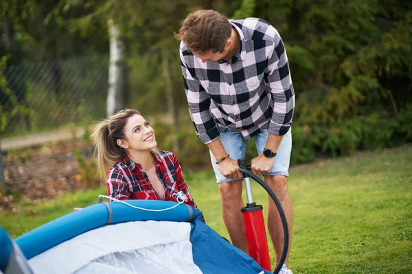 Jovem casal agradável se divertindo no acampamento criação de tenda — Fotografia de Stock