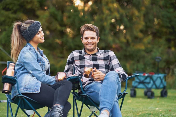 Unga trevliga par sitter på stolar framför tältet på camping — Stockfoto