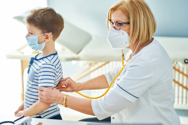 Médico pediatra examinando a niños pequeños en clínica —  Fotos de Stock