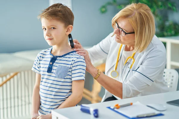 Médico pediatra examinando a niños pequeños en clínica —  Fotos de Stock