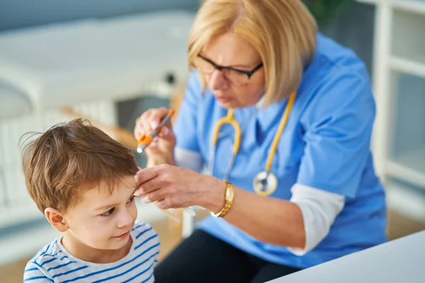 Kinderarts arts onderzoeken van kleine kinderen in kliniek oren controleren — Stockfoto